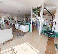 Innenraum eines Einfamilienhauses mit moderner Küchenzeile, Wendeltreppe und grünen Fliesen.