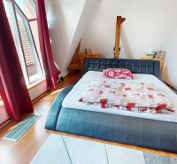 Schlafzimmer in einem Einfamilienhaus mit großem Fenster, Bett und Boden mit Holzdekor.