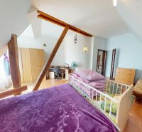 Dachbodenschlafzimmer in einem Einfamilienhaus mit Holzboden und Holzbalken.