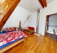 Ein Dachzimmer in einem Einfamilienhaus mit einem Bett, dekorativem Holz und einem Boden mit Holzdekor.