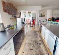 Eine Küche in einem Einfamilienhaus mit schwarzen Arbeitsplatten und dekorativer Kunst an der Wand.