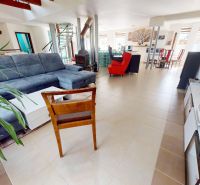 Wohnzimmer in einem Einfamilienhaus mit bequemer Couch, Kamin und Essecke.