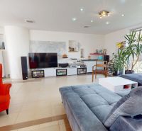 Wohnzimmer in einem Einfamilienhaus mit einem großen Sofa und einem roten Sessel.