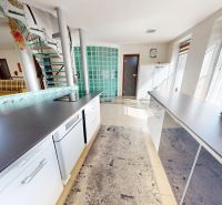Küche in einem Einfamilienhaus mit weißen Schränken und Treppe, Glasbausteine und Tageslicht.