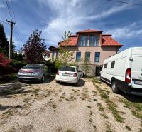 Ein Einfamilienhaus in Veľké Chlievany mit drei geparkten Autos auf einem Kiesgrundstück.