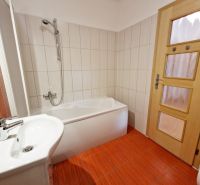 Badezimmer mit hellen Fliesen und rotem Bodenbelag in einer 3-Zimmer-Wohnung.