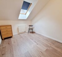 Ein Zimmer in einer 3-Zimmer-Wohnung mit einem Boden in Holzoptik, einer Kommode und einem Stuhl.