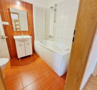 Badezimmer in einer 3-Zimmer-Wohnung mit Badewanne und Waschbecken, Boden mit Holzdekor.
