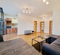 Wohnzimmer in einer 3-Zimmer-Wohnung mit grauem Sofa und Boden in Holzoptik.