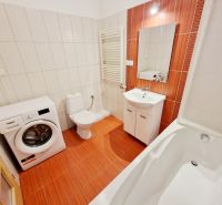 Badezimmer in einer 3-Zimmer-Wohnung mit Dusche, Waschmaschine und orangefarbenen Fliesen.