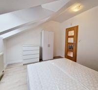 Dachbodenschlafzimmer in einer 3-Zimmer-Wohnung mit weißen Möbeln und einem Boden in Holzoptik.