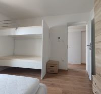 Ein Schlafzimmer mit einem Etagenbett, einem Boden mit Holzdekor und Stauraum in einem Einfamilienhaus.