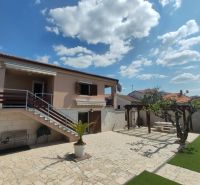 Ein Einfamilienhaus in Bibinje mit Treppen, Terrasse und Laubengang, umgeben von einem Garten.
