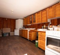 Küche in einem Einfamilienhaus mit Holzschränken und einem Boden in Holzoptik.