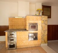 Kachelofen im Einfamilienhaus mit Keramikverkleidung und Holzdekor an den Wänden.