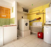 Heizraum im Einfamilienhaus mit Waschmaschine, Trockner und Boiler, helle Fliesen.
