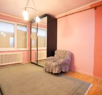 Ein Zimmer in einem Einfamilienhaus mit einem Boden in Holzoptik, einem Spiegelschrank und einem Sessel.