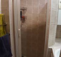 Duschkabine im Badezimmer mit Fliesen in einer 2-Zimmer-Wohnung.