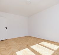 Ein leeres Zimmer in einer 3-Zimmer-Wohnung mit einem Boden in Holzoptik.