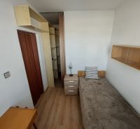 Ein Zimmer in einer Einzimmerwohnung mit Holzboden, Bett und Regalen.