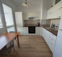 Küche in einer Einzimmerwohnung mit weißen Schränken und einem Holzboden.