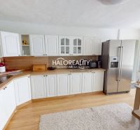Küche in einem Einfamilienhaus mit weißen Schränken, Kühlschrank und Holzboden.