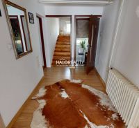 Innenraum eines Einfamilienhauses mit Holzboden und Treppe mit Geländer.