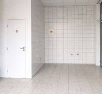 Gewerbeflächen mit hellem Boden, weißen Fliesen und Holzelementen an der Wand.