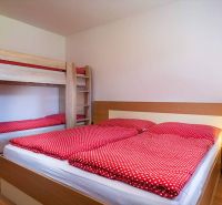 Das Ferienapartment bietet ein komfortables Schlafzimmer mit einem Etagenbett und einem Boden in Holzoptik.