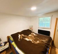 Eine Hütte mit Holzboden, Bett und Nachttisch, einfaches Schlafzimmerdesign.