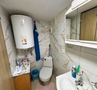 Ein Badezimmer mit Fliesen und Boiler bietet grundlegende Hygieneartikel und Stauraum.
