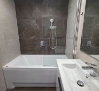Badezimmer in einer 3-Zimmer-Wohnung mit Badewanne, Duschwand und modernem Waschbecken.