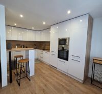 Küche in einer 3-Zimmer-Wohnung mit Bar-Sitzgelegenheiten und einem Boden in Holzoptik.