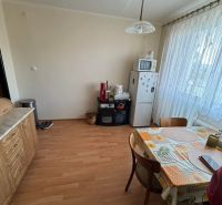 Küche in einer Einzimmerwohnung mit Holzboden, Esstisch und Geräten.