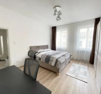 Helles Schlafzimmer mit Holzdekorboden und Schreibtisch in einer 3-Zimmer-Wohnung.