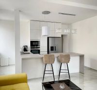 Küche in einer 3-Zimmer-Wohnung mit Insel, Barhockern und hellen Schränken.