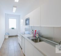 Büroküche mit hellen Möbeln und Geräten, mit einem Boden in Holzoptik.