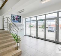 Innenraum eines Büros mit Treppe, Briefkästen und großen Glastüren.
