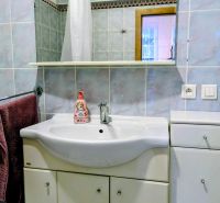 Badezimmer in einer 2-Zimmer-Wohnung mit Waschbecken, Spiegel und blauen Fliesen.