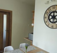 Interieur einer 2-Zimmer-Wohnung mit einer Uhr an der Wand, Holztüren und einem Tisch.