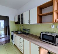 Küche in einer 2-Zimmer-Wohnung mit Mikrowelle und Kochfeld, die in einen weiteren Raum führt.