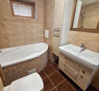 Badezimmer mit Eckbadewanne, Waschbecken und Toilette in einer 2-Zimmer-Wohnung.