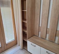 Ein hölzerner Kleiderständer mit Stauraum am Fenster in einer 2-Zimmer-Wohnung.