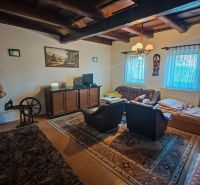 Wohnzimmer mit Teppich, Holzbalkendecke und Fernseher in einem Einfamilienhaus.