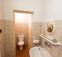 Badezimmer in einem Einfamilienhaus mit Waschbecken, Spiegel und Toilette, Fliesen mit braunem Dekor.