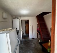 Innenraum eines Einfamilienhauses mit Kühlschrank, Boiler und Holztreppe.