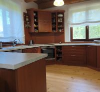 Küche in einem Einfamilienhaus mit Schränken aus dunklem Holz und einem Boden in Holzoptik.