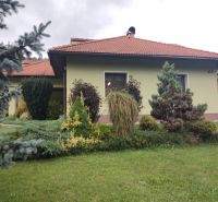 Ein Einfamilienhaus in Trebostovo, vorne ein gepflegter Garten mit Pflanzen und Bäumen.