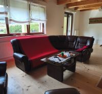Wohnzimmer in einem Einfamilienhaus mit Ledersofas und einem Boden in Holzoptik.