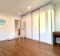 Ein Zimmer in einer 3-Zimmer-Wohnung mit einem Boden in Holzoptik, einem Einbauschrank und einem Spiegel.
